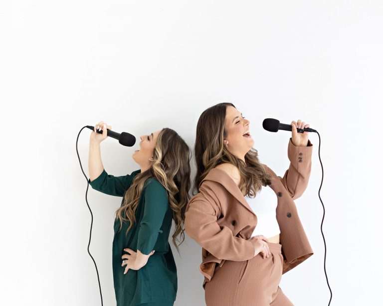 Two female podcasters during their personal branding session with The Portrait Mama holding microphones