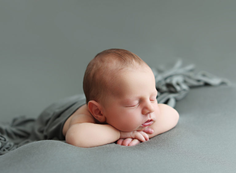 Newborn baby peacefully sleeping on a soft blanket, photographed with expertise in a San Diego newborn photography studio.