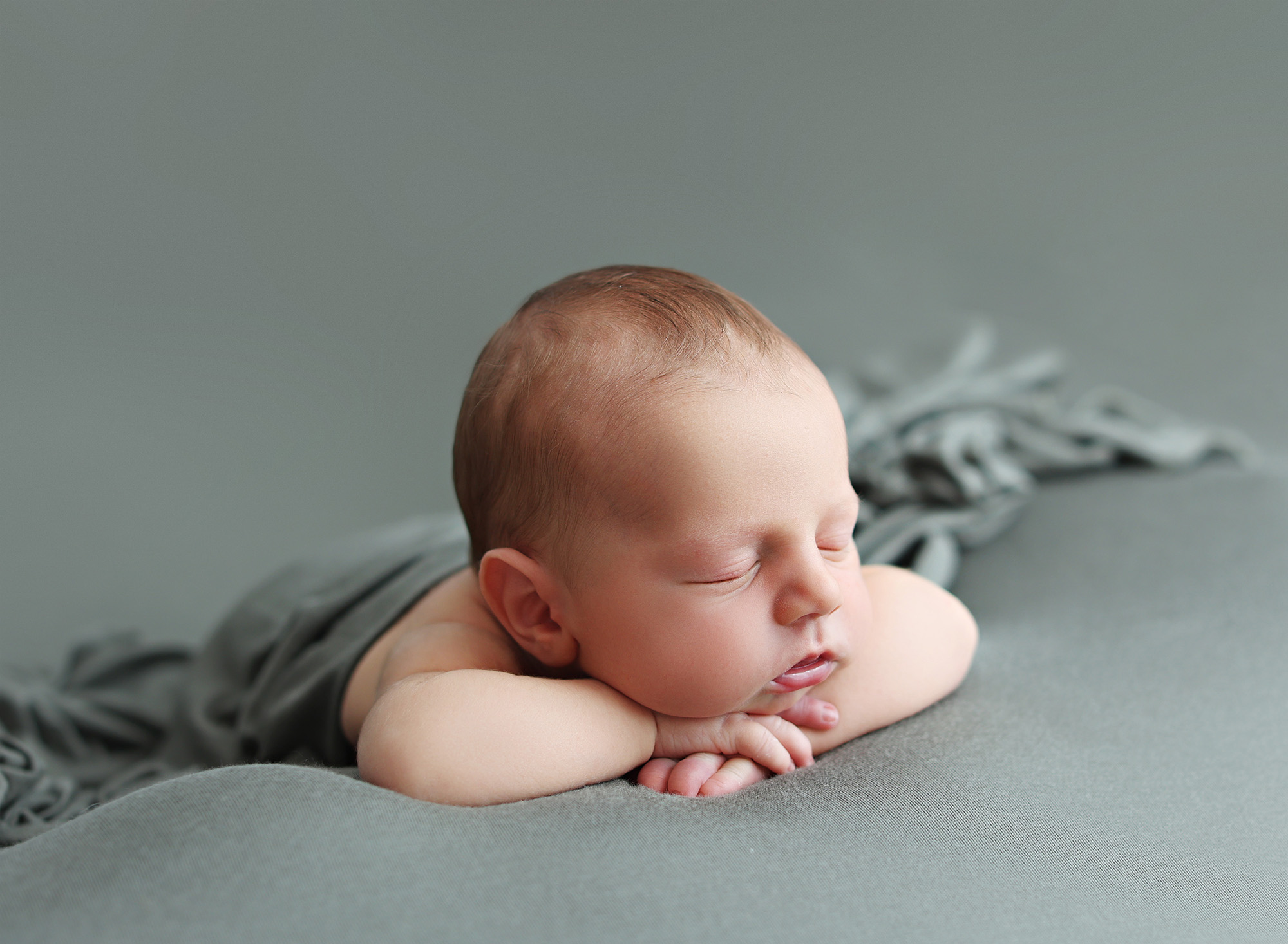 Newborn baby peacefully sleeping on a soft blanket, photographed with expertise in a San Diego newborn photography studio.