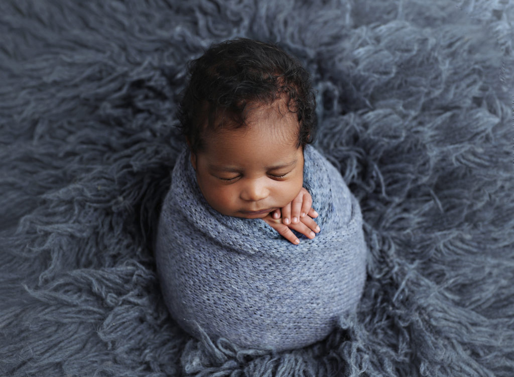 Newborn baby peacefully sleeping in a cozy wrap, captured by San Diego's premier maternity and newborn photographer.