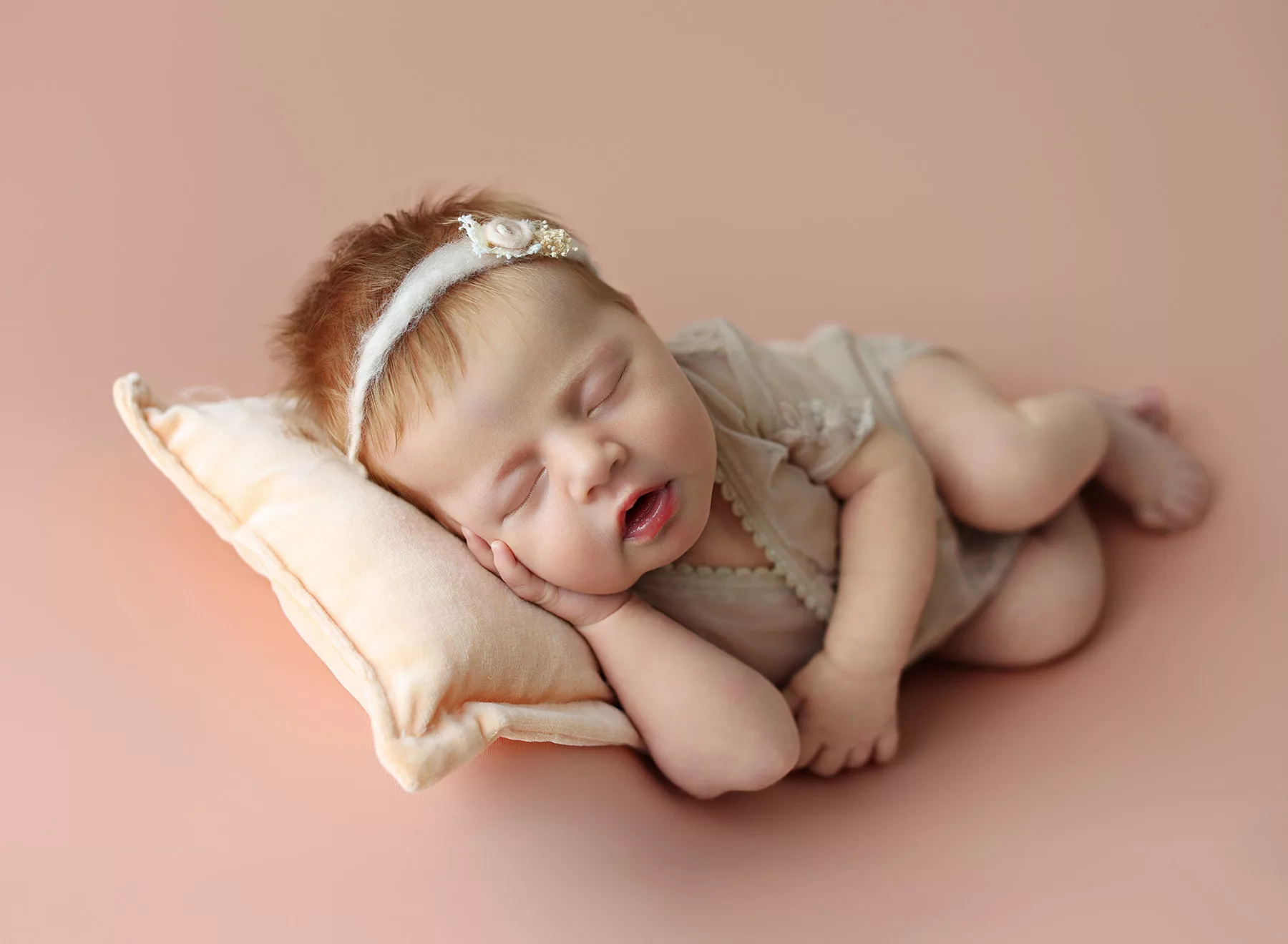 La Jolla newborn photographer capturing baby girl in soft natural light - San Diego Maternity, Newborn, and Brand Photographer Newborn baby girl wearing a floral headband, captured in La Jolla studio.